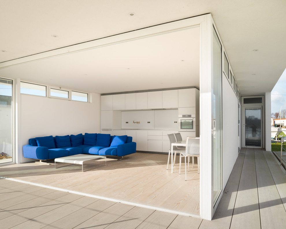 Ejemplo de salón para visitas abierto moderno con paredes blancas y suelo de madera clara