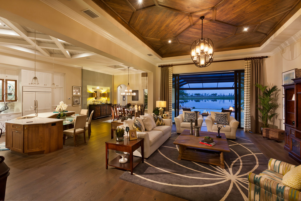 Ejemplo de salón para visitas abierto tradicional extra grande con paredes beige, suelo de madera en tonos medios y televisor colgado en la pared