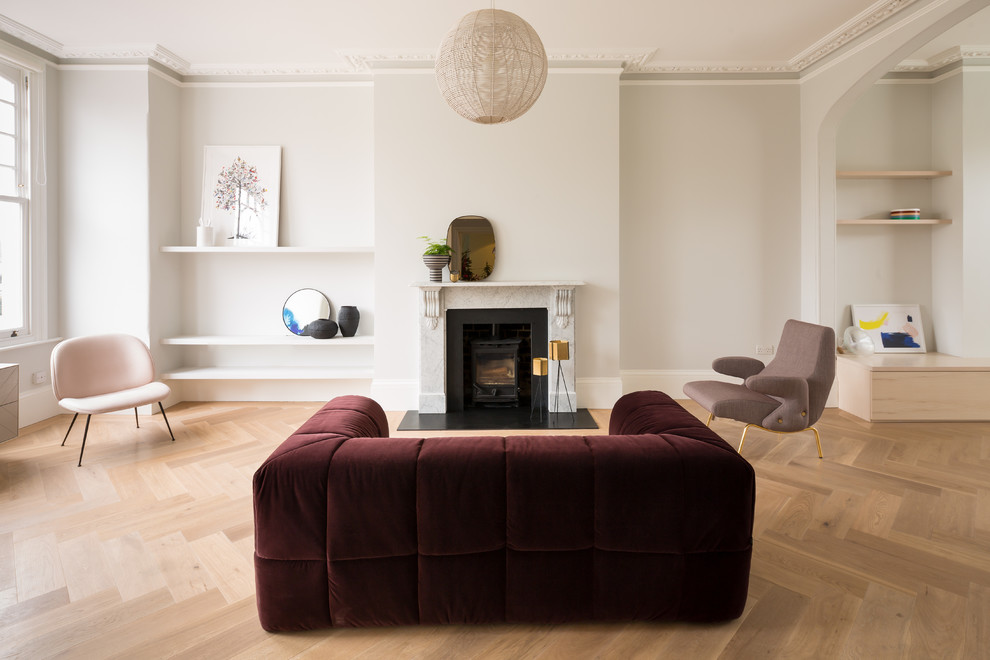 Contemporary formal open plan living room in London with beige walls, light hardwood flooring, a wood burning stove, a metal fireplace surround and beige floors.