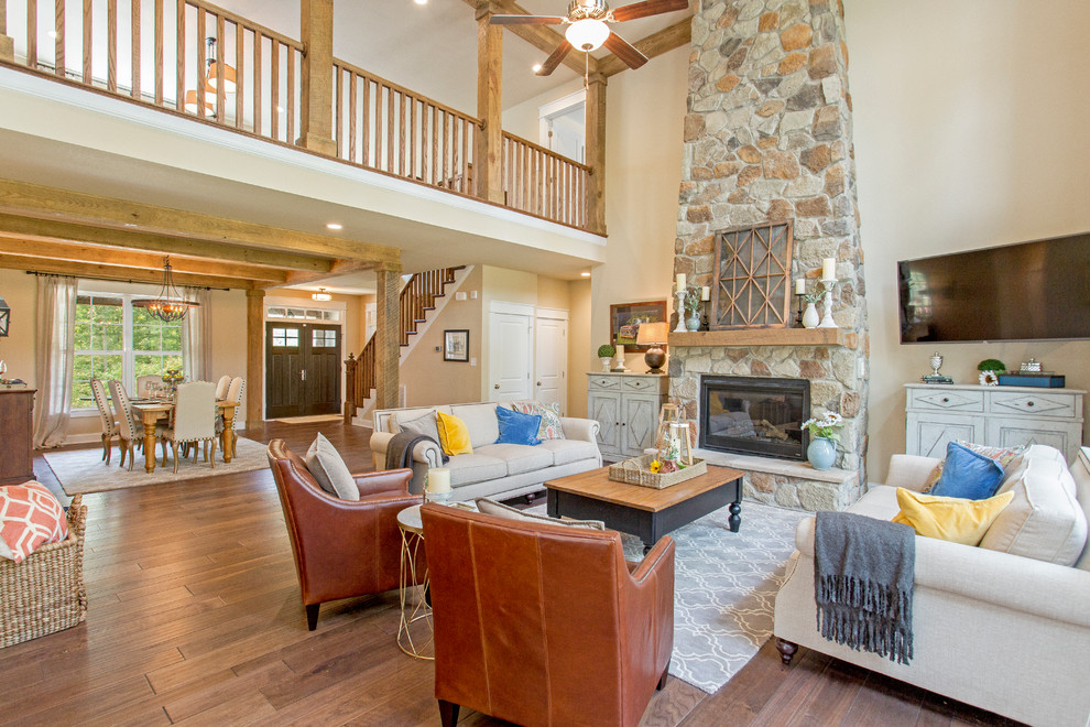 Example of a large arts and crafts open concept and formal medium tone wood floor living room design in Richmond with beige walls, a standard fireplace, a stone fireplace and a wall-mounted tv
