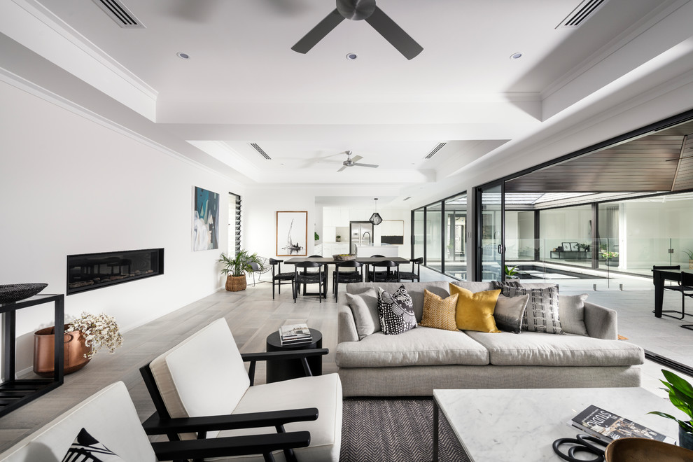Geräumiges, Offenes Modernes Wohnzimmer ohne Kamin mit weißer Wandfarbe, Kaminumrandung aus Metall, TV-Wand und grauem Boden in Perth