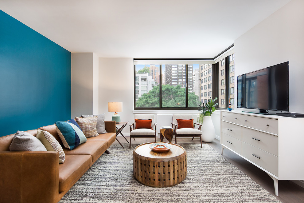 Example of a trendy dark wood floor and brown floor living room design in New York with blue walls and a tv stand