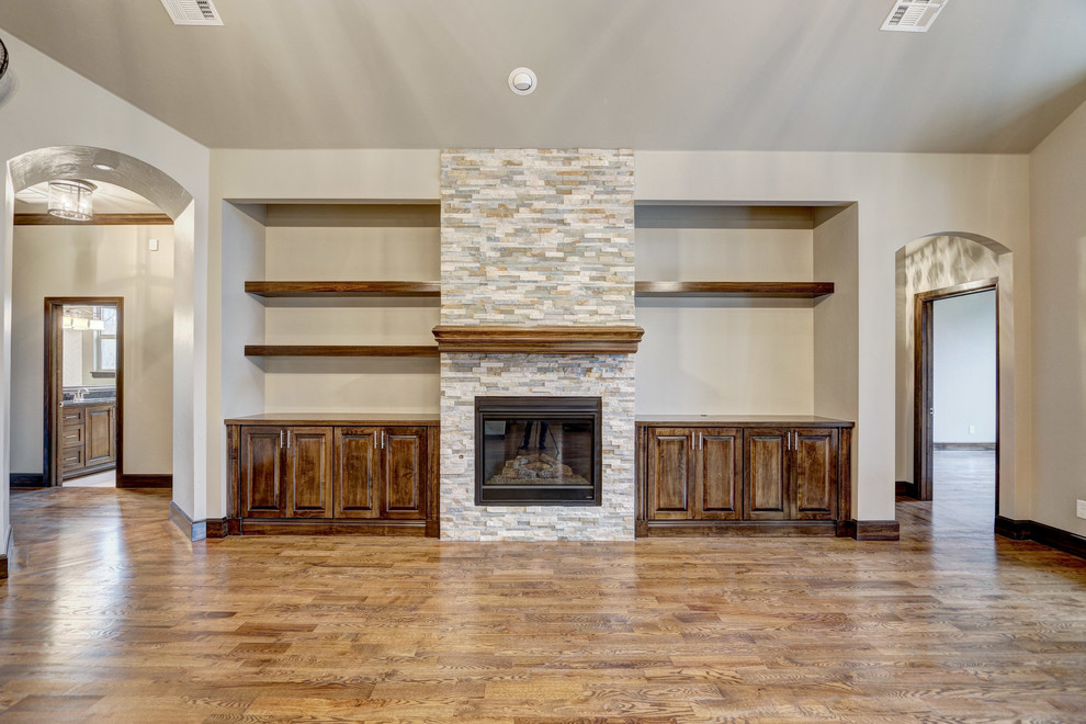Inspiration for a large classic open plan living room in Oklahoma City with beige walls, medium hardwood flooring, a standard fireplace, a stone fireplace surround and a built-in media unit.