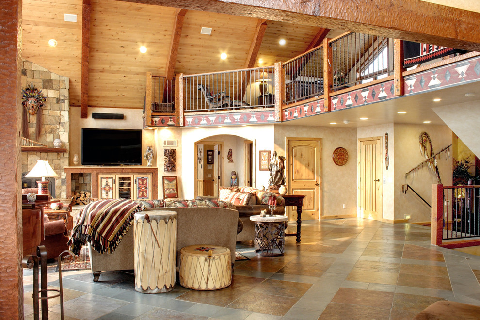 Esempio di un ampio soggiorno rustico aperto con pareti beige, pavimento in ardesia, cornice del camino in pietra e TV autoportante