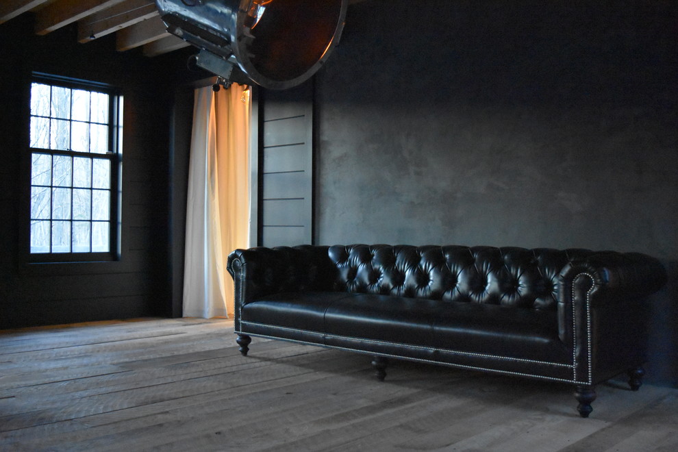 Industrial Wohnzimmer mit schwarzer Wandfarbe, braunem Holzboden, Kamin und Kaminumrandung aus Beton in New York