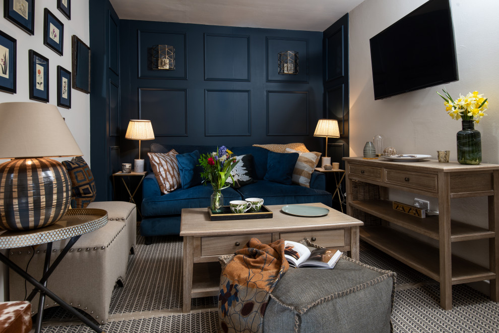 На фото: маленькая изолированная гостиная комната в стиле неоклассика (современная классика) с синими стенами, паркетным полом среднего тона, печью-буржуйкой, телевизором на стене и коричневым полом для на участке и в саду