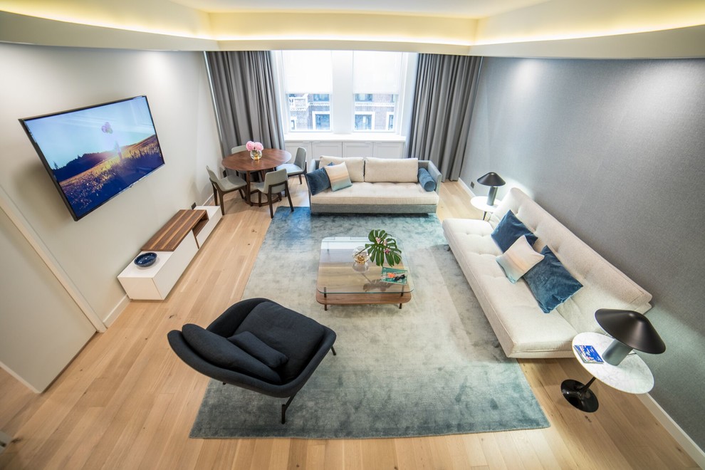 Immagine di un soggiorno minimalista di medie dimensioni e aperto con sala formale, pareti blu, parquet chiaro, nessun camino, TV a parete e pavimento beige