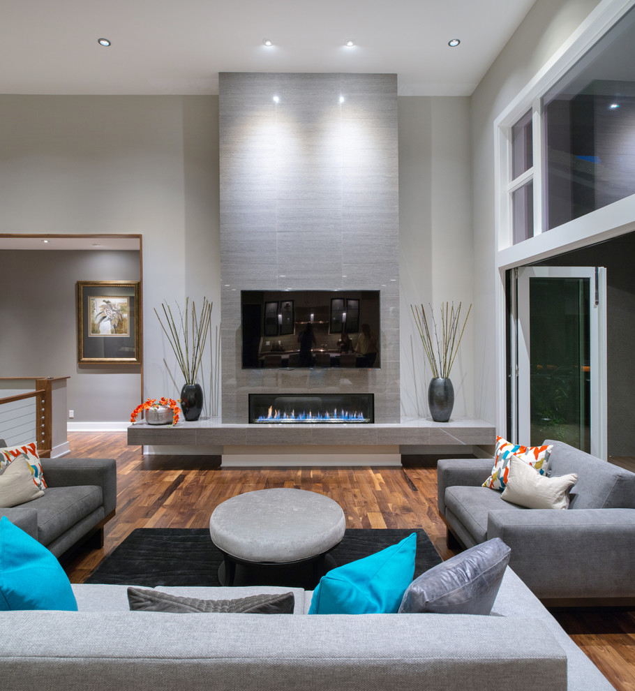 Large trendy medium tone wood floor living room photo in Kansas City with gray walls and a tile fireplace