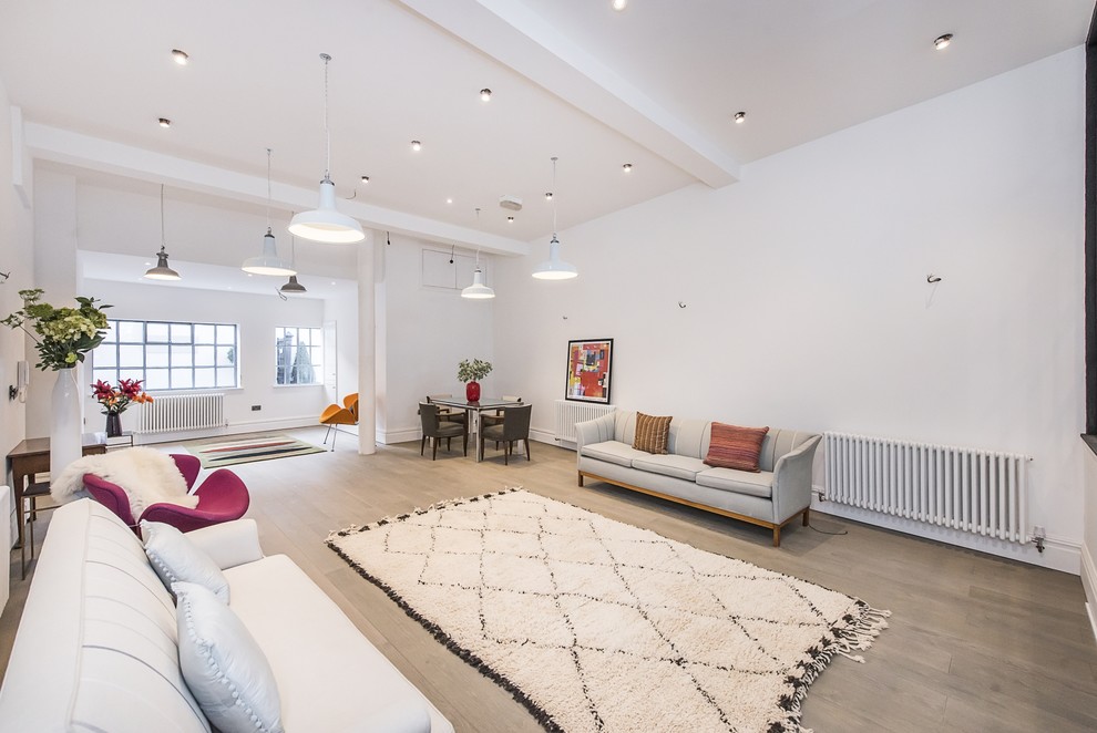 Medium sized contemporary formal open plan living room in London with white walls, light hardwood flooring, no fireplace, a plastered fireplace surround, no tv and grey floors.