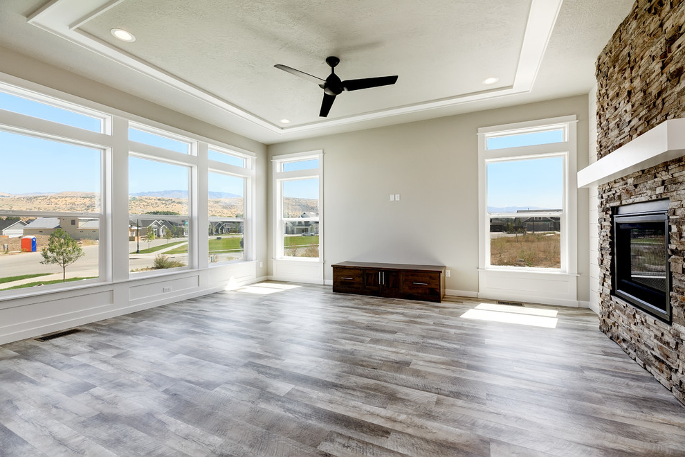 Example of a large transitional formal and open concept vinyl floor and gray floor living room design in Boise with gray walls, a standard fireplace, a stone fireplace and no tv