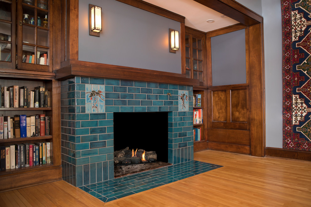 ミネアポリスにある高級な中くらいなトラディショナルスタイルのおしゃれなLDK (ライブラリー、グレーの壁、セラミックタイルの床、標準型暖炉、タイルの暖炉まわり、テレビなし、青い床) の写真