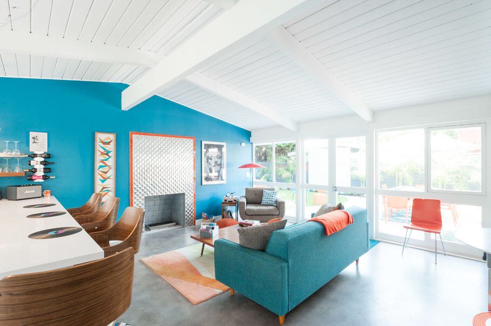 Идея дизайна: открытая гостиная комната в стиле ретро с синими стенами, стандартным камином, фасадом камина из металла, серым полом и акцентной стеной