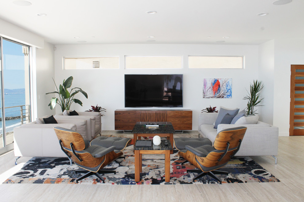Modelo de salón abierto y blanco moderno grande con paredes blancas, suelo de travertino, televisor colgado en la pared y suelo beige