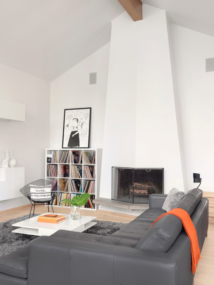 Photo of a scandinavian living room in St Louis with white walls, light hardwood flooring, a standard fireplace and a plastered fireplace surround.