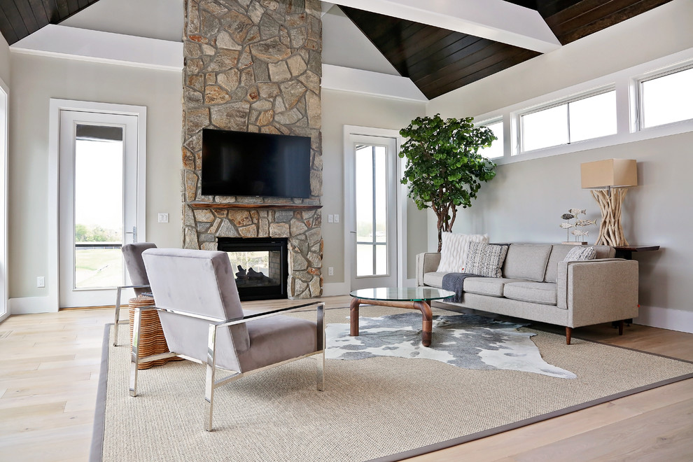 Large transitional open concept light wood floor and beige floor living room photo in Other with beige walls, a two-sided fireplace, a stone fireplace and a wall-mounted tv