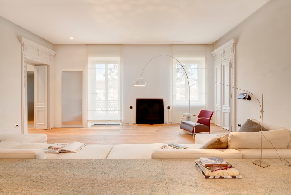 Immagine di un soggiorno minimal aperto con libreria, pareti bianche, parquet chiaro, camino classico e TV autoportante