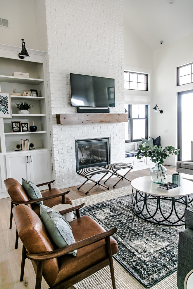Living room - mid-sized farmhouse formal and open concept medium tone wood floor and brown floor living room idea in Salt Lake City with white walls, a standard fireplace, a brick fireplace and a wall-mounted tv