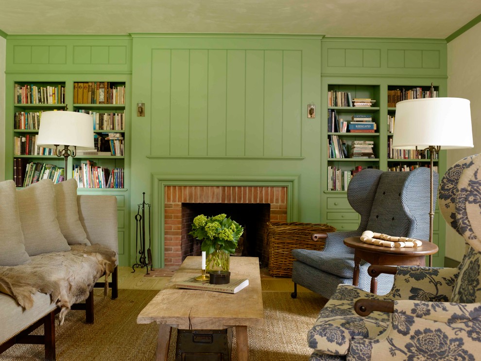 Cette photo montre un salon nature fermé avec une bibliothèque ou un coin lecture, un mur vert, parquet clair, une cheminée standard, un manteau de cheminée en brique et aucun téléviseur.