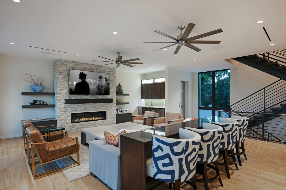 Inspiration for a mid-sized modern open concept porcelain tile and brown floor living room remodel in Tampa with a bar, white walls, a ribbon fireplace, a stone fireplace and a wall-mounted tv