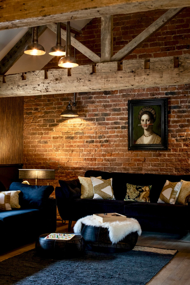 Cette image montre un salon bohème de taille moyenne et ouvert avec un sol en bois brun, un poêle à bois, un manteau de cheminée en métal, un téléviseur fixé au mur, un sol marron, un plafond voûté et un mur en parement de brique.