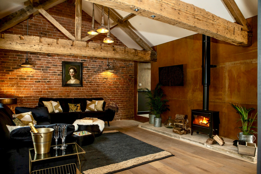 Modelo de salón abierto y abovedado bohemio de tamaño medio con suelo de madera en tonos medios, estufa de leña, televisor colgado en la pared, suelo marrón y ladrillo