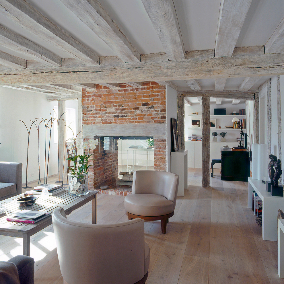 Пример оригинального дизайна: открытая гостиная комната среднего размера в современном стиле с белыми стенами, светлым паркетным полом, двусторонним камином и фасадом камина из кирпича без телевизора