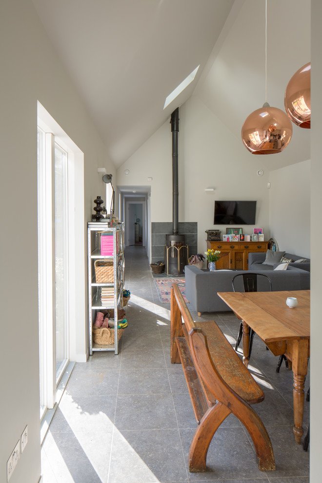 Foto di un piccolo soggiorno contemporaneo aperto con pareti bianche, pavimento in vinile, stufa a legna, cornice del camino in pietra e TV a parete