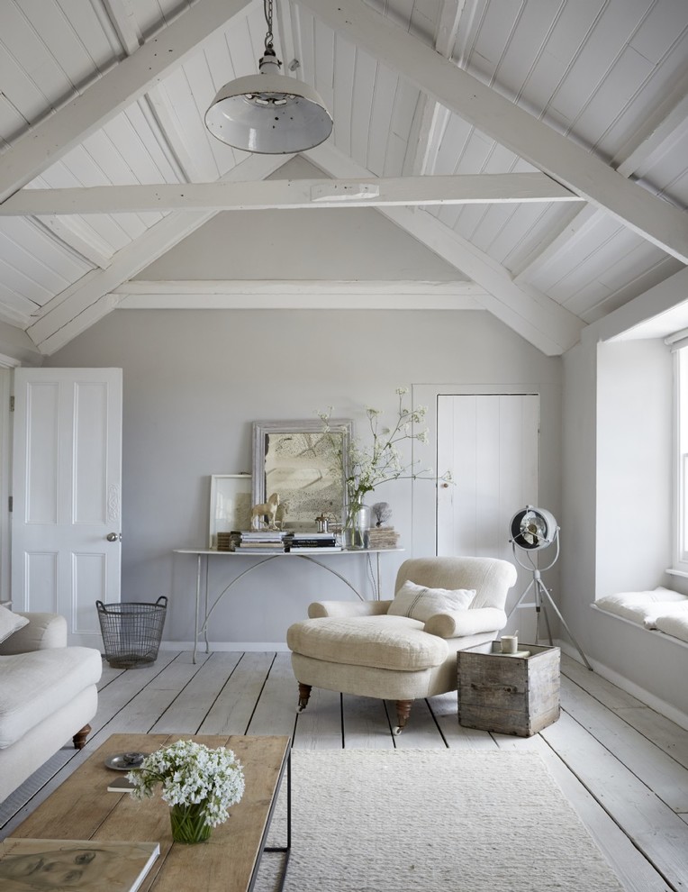 Réalisation d'un grand salon champêtre avec un mur blanc, parquet peint, un poêle à bois, un manteau de cheminée en bois et un sol blanc.