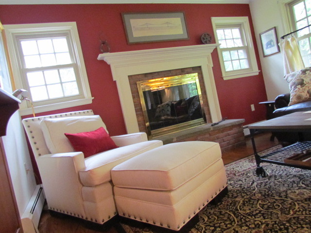 Inredning av ett klassiskt mellanstort separat vardagsrum, med ett finrum, röda väggar, mörkt trägolv, en standard öppen spis, en spiselkrans i tegelsten och brunt golv