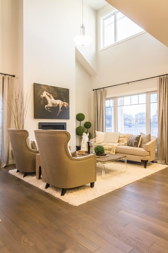 Photo of a large classic open plan living room in Calgary with white walls, medium hardwood flooring, a standard fireplace and a plastered fireplace surround.
