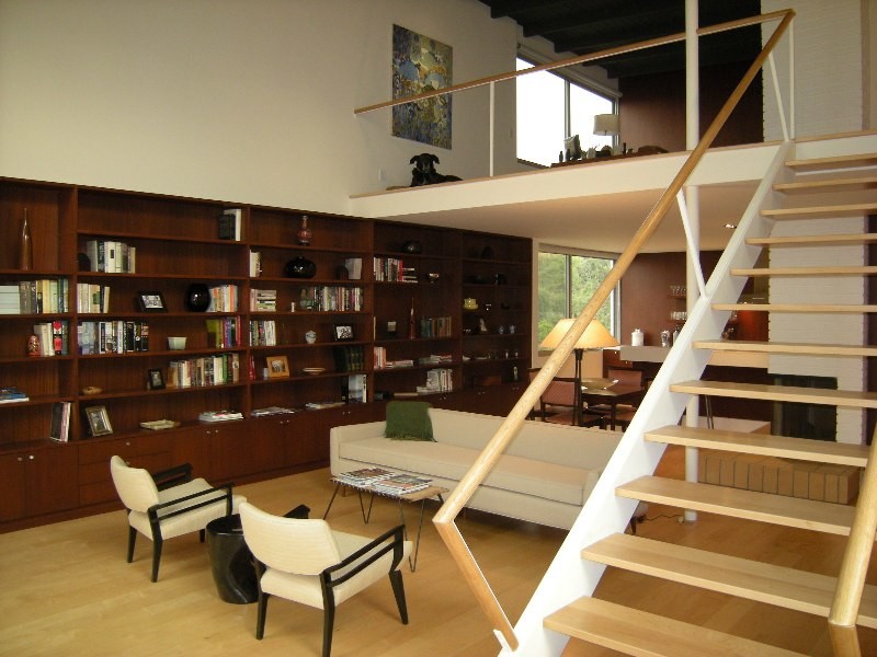 Пример оригинального дизайна: двухуровневая гостиная комната среднего размера в стиле ретро с с книжными шкафами и полками, белыми стенами, светлым паркетным полом, двусторонним камином и фасадом камина из кирпича