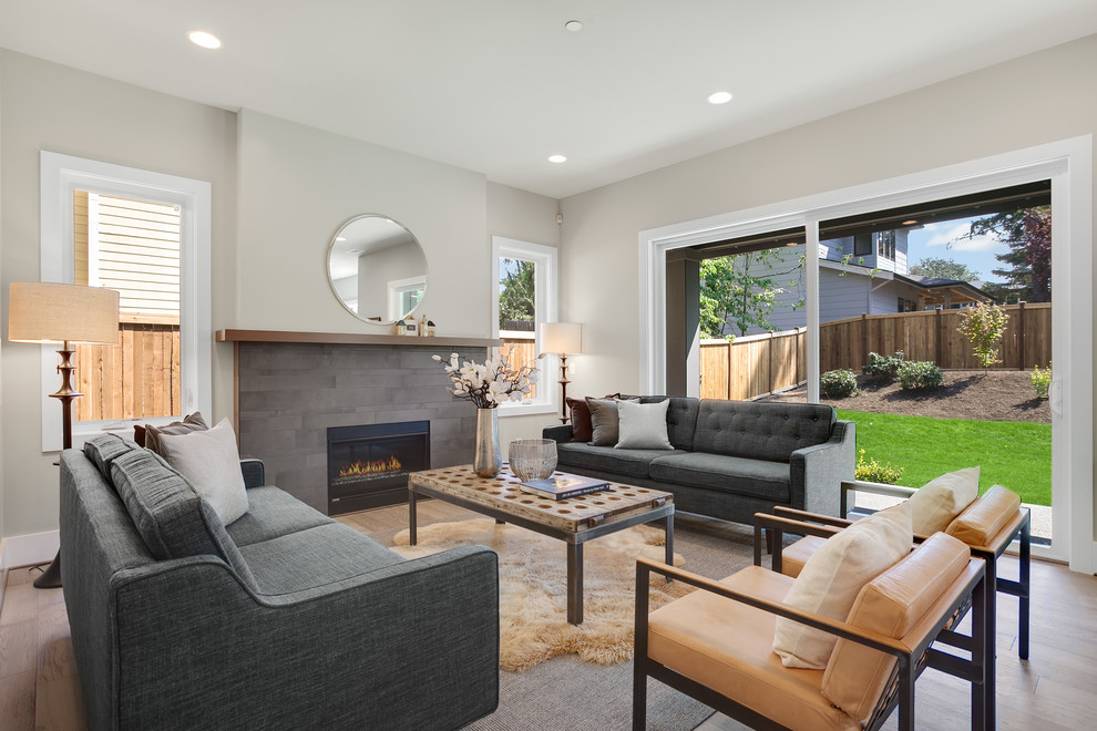 Design ideas for a medium sized classic open plan living room in Seattle with grey walls, light hardwood flooring, a standard fireplace, a tiled fireplace surround and grey floors.