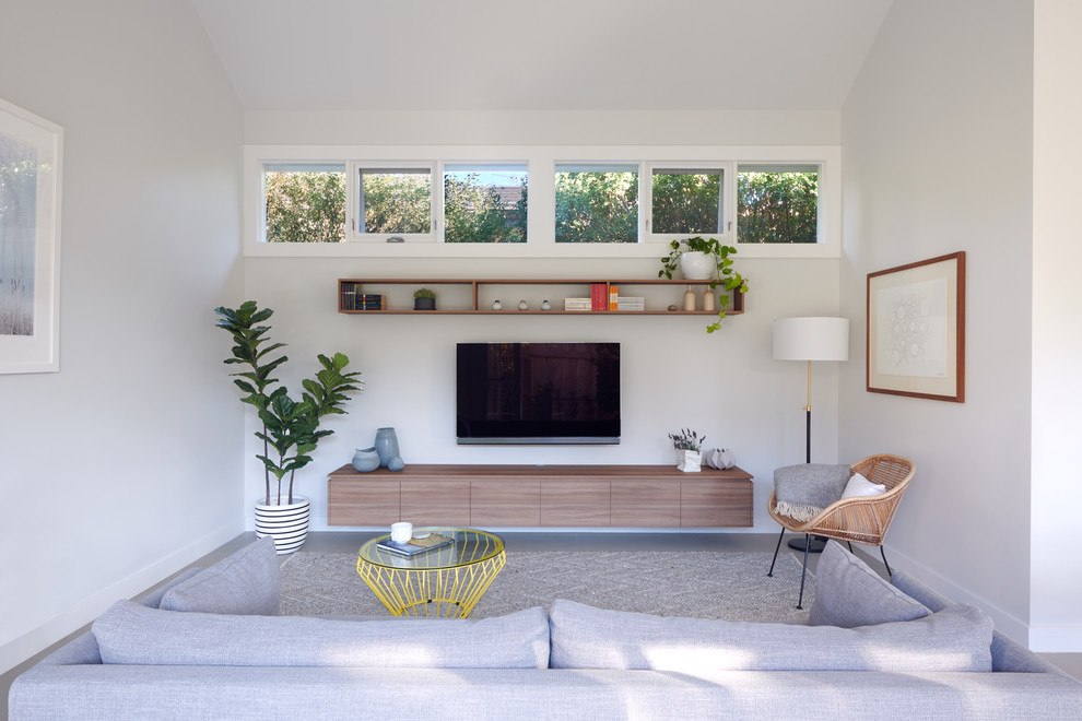 Ispirazione per un soggiorno tradizionale con pareti beige, pavimento in cemento e TV a parete