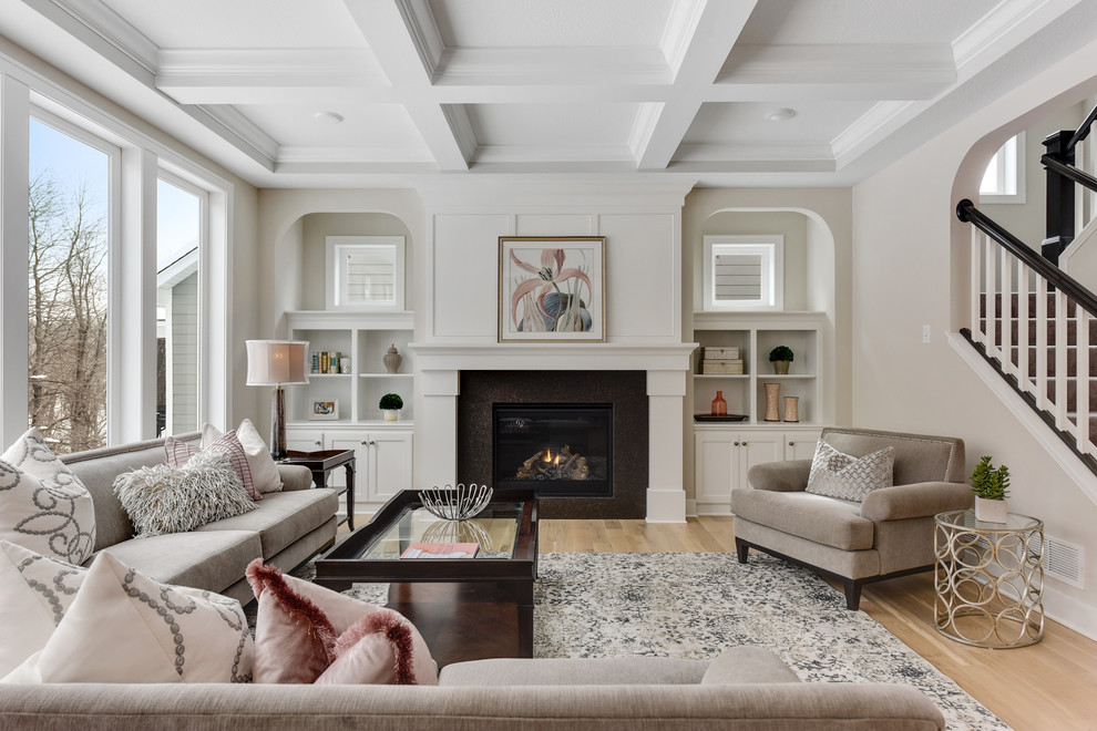 Diseño de salón abierto clásico renovado con paredes beige, suelo de madera clara, todas las chimeneas y suelo beige