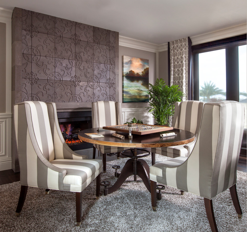 This is an example of a traditional dining room in San Diego with grey walls, dark hardwood flooring, a standard fireplace and a concrete fireplace surround.