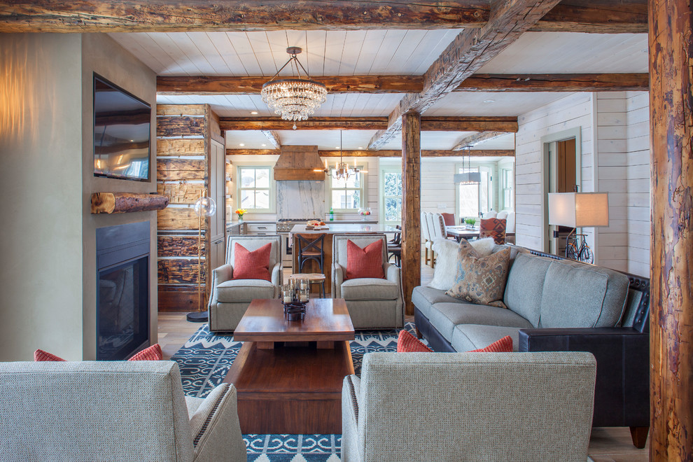 Example of a mountain style formal and open concept medium tone wood floor and brown floor living room design in Denver with multicolored walls, a standard fireplace, a wall-mounted tv and a plaster fireplace