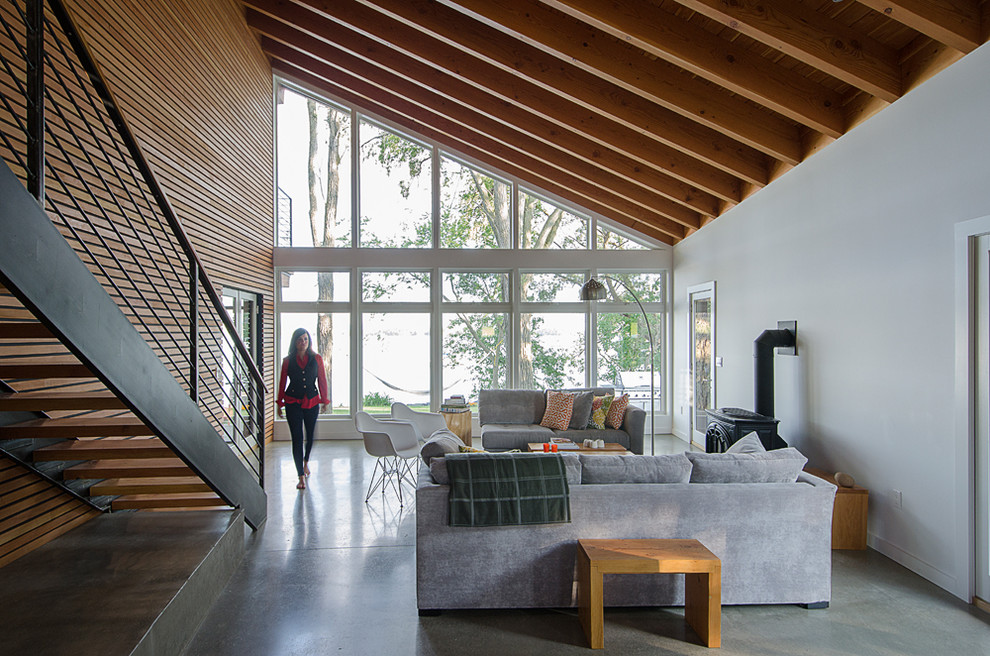 Ispirazione per un soggiorno minimal di medie dimensioni e aperto con pavimento in cemento, stufa a legna e pavimento grigio