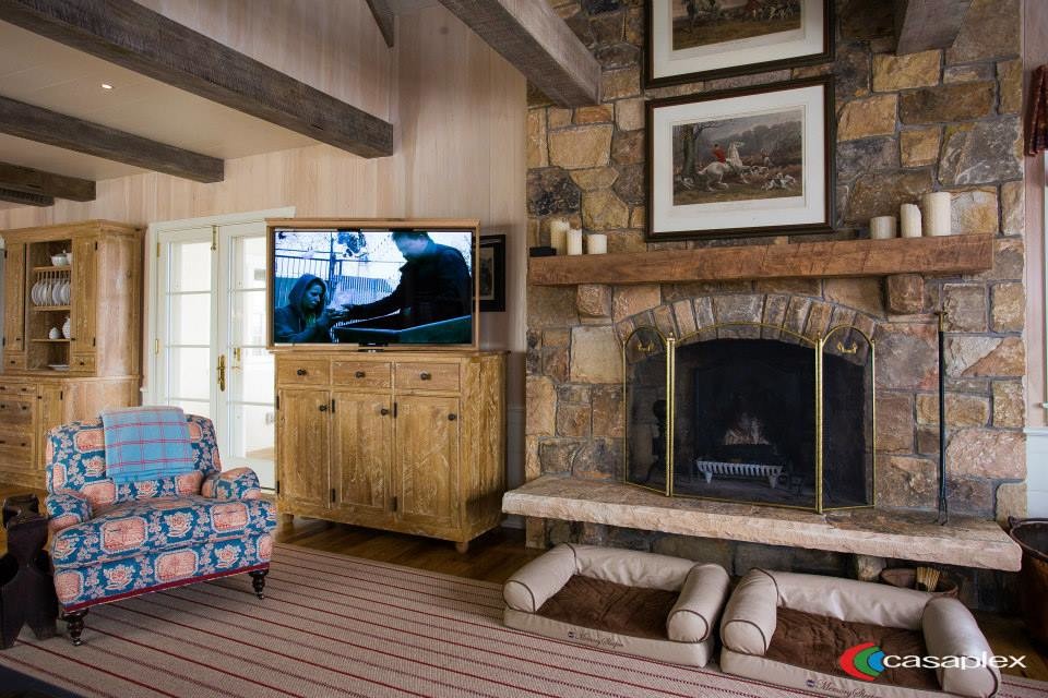 Cette image montre un salon traditionnel ouvert avec un mur multicolore, un sol en bois brun, une cheminée standard, un manteau de cheminée en pierre et un téléviseur dissimulé.