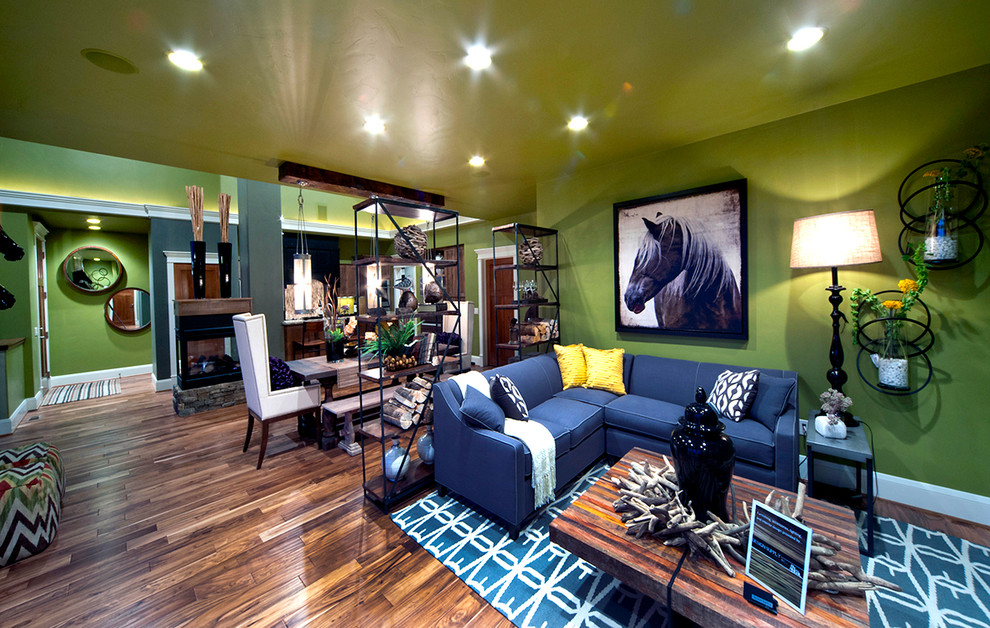 Kleines, Offenes Landhaus Wohnzimmer mit grüner Wandfarbe, braunem Holzboden, Tunnelkamin, Kaminumrandung aus Stein und TV-Wand in Sonstige