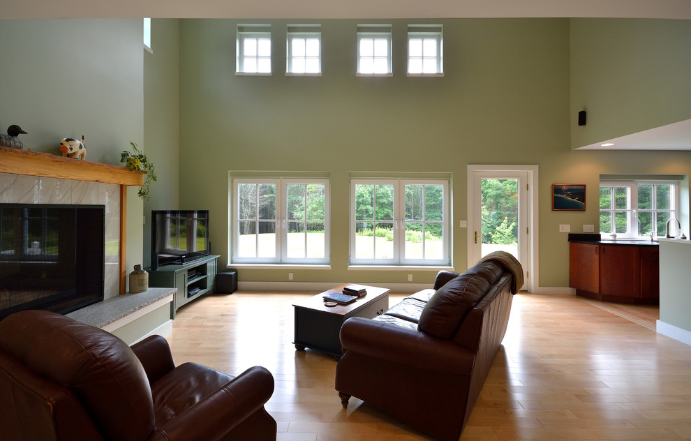 Источник вдохновения для домашнего уюта: двухуровневая гостиная комната в стиле кантри с зелеными стенами, светлым паркетным полом, двусторонним камином, фасадом камина из плитки и телевизором в углу