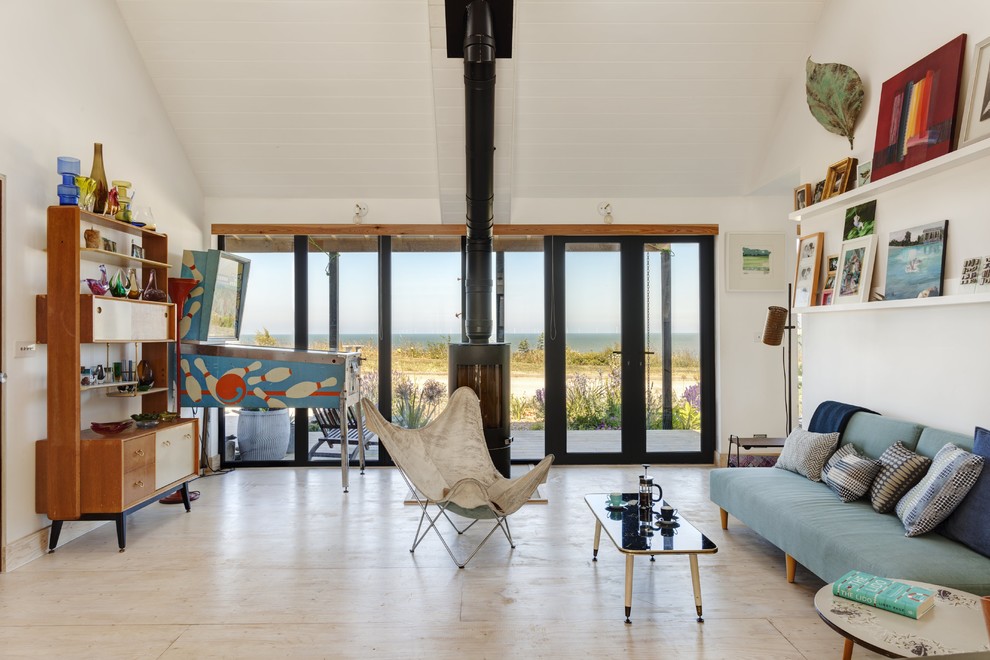 Immagine di un soggiorno stile marino con pareti bianche, pavimento in compensato, stufa a legna e pavimento beige