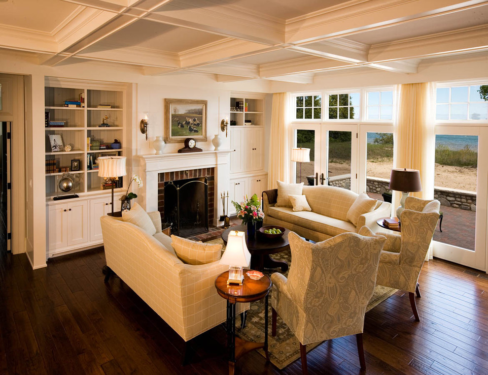 Inspiration pour un grand salon traditionnel ouvert avec un manteau de cheminée en brique, une salle de réception, un mur beige, un sol en bois brun, une cheminée standard, aucun téléviseur et un sol marron.