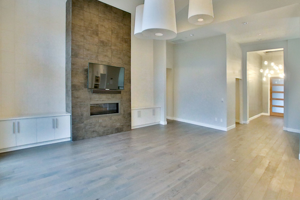 Offenes, Großes Modernes Wohnzimmer mit weißer Wandfarbe, braunem Holzboden, Gaskamin, TV-Wand und Kaminumrandung aus Stein in Portland