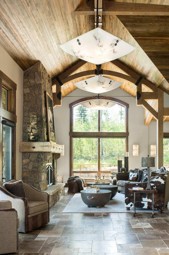 Inspiration for a large rustic open plan living room in Denver with beige walls, a standard fireplace, a stone fireplace surround, no tv, brown floors and travertine flooring.