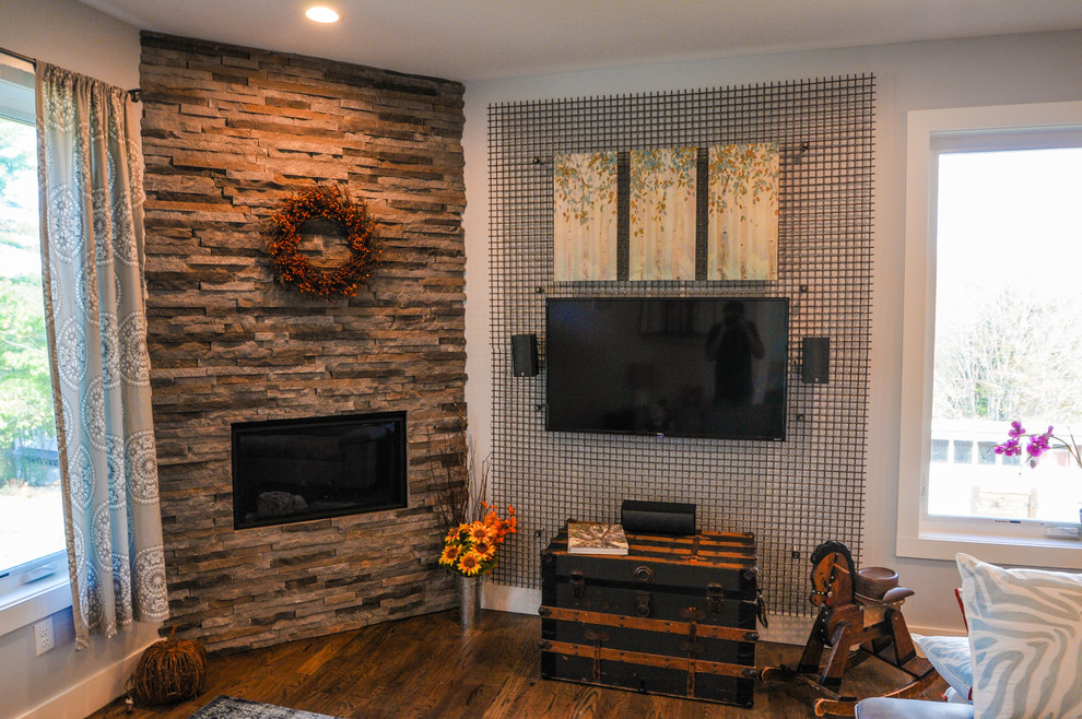 Foto de salón cerrado clásico renovado pequeño con paredes grises, suelo de madera oscura, chimenea de esquina, marco de chimenea de piedra, televisor colgado en la pared y suelo marrón