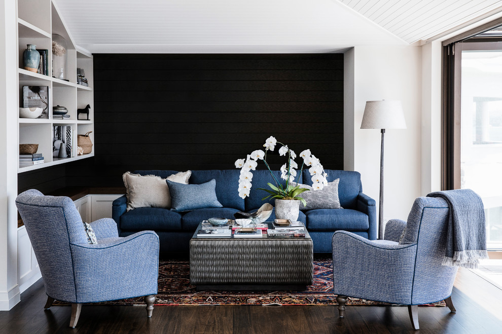 На фото: парадная гостиная комната в стиле неоклассика (современная классика) с белыми стенами, темным паркетным полом, коричневым полом и синим диваном с