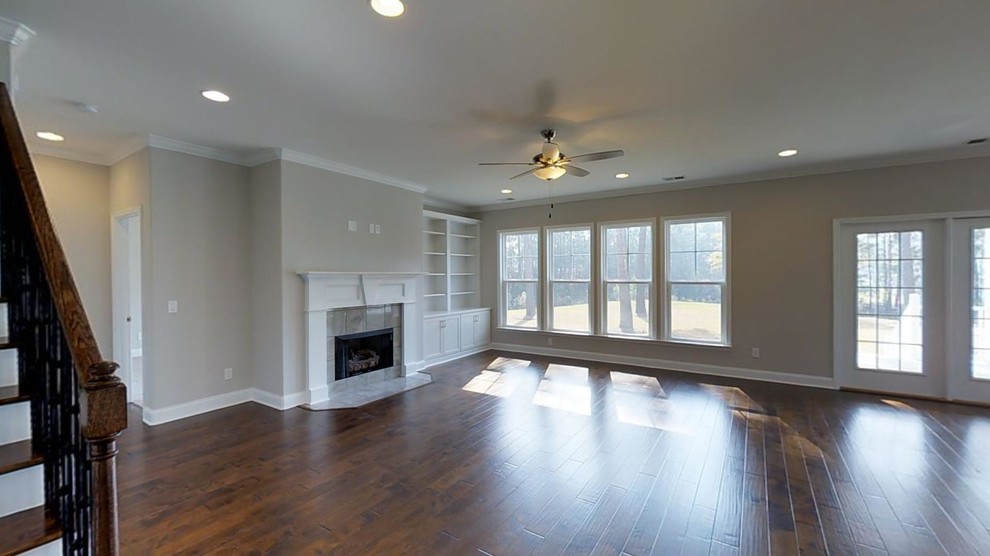 Example of a large classic open concept medium tone wood floor and brown floor living room design in Atlanta with a standard fireplace, a wall-mounted tv, a tile fireplace and beige walls