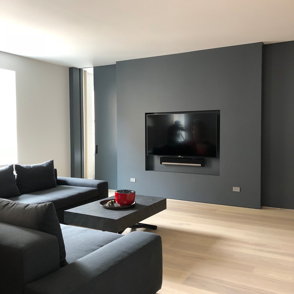 Modern inredning av ett mellanstort loftrum, med grå väggar, ljust trägolv, en inbyggd mediavägg och beiget golv