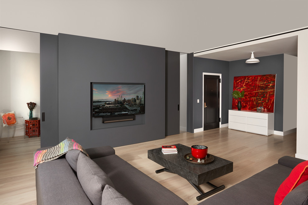 Cette photo montre un salon mansardé ou avec mezzanine moderne de taille moyenne avec un mur gris, parquet clair, un téléviseur encastré et un sol beige.