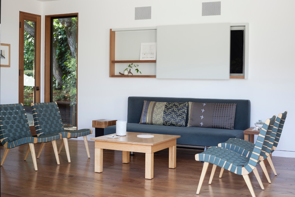 Foto di un soggiorno minimal con sala formale, pareti bianche, pavimento in legno massello medio e TV nascosta